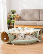 Load image into Gallery viewer, Gray cat resting inside a collapsible green cat tunnel with hanging toys on a wooden floor in a living room.