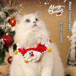 Load image into Gallery viewer, White cat wearing a red and white Christmas scarf with pom-poms and Santa design next to decorated Christmas tree background
