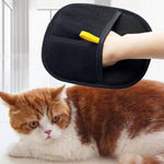Load image into Gallery viewer, Hand wearing black pet hair remover glove brushing orange and white cat indoors by window light