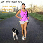 Load image into Gallery viewer, Woman jogging with a black and white dog using a hands-free dog leash with shoulder strap on a paved path outdoors
