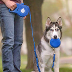 Load image into Gallery viewer, Person holding a blue 2-in-1 pet leash with water bottle attachment and a husky dog outdoors on a walk