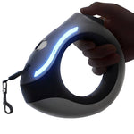 Load image into Gallery viewer, Hand holding a ring-shaped retractable pet leash with glowing LED light for safe night walks