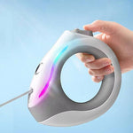 Load image into Gallery viewer, Hand holding a ring-shaped retractable pet leash with built-in LED light for safe night walks