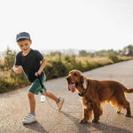 Load image into Gallery viewer, Young boy walking a dog on leash with a portable degradable dog poop bag dispenser attached to the leash.