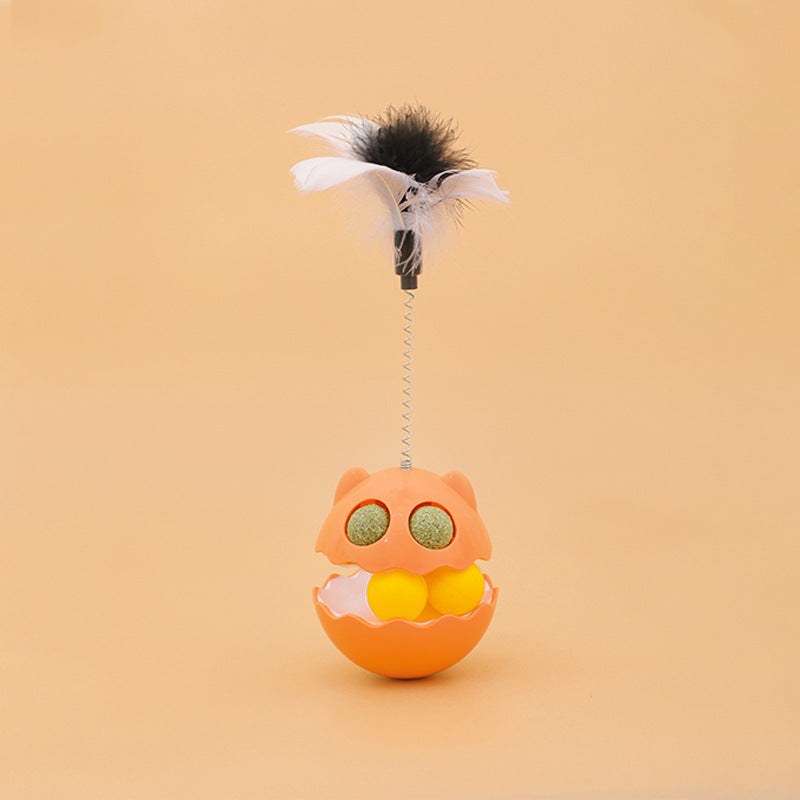 Orange cat-shaped rotating feather toy with track balls and catnip for interactive pet play on tan background