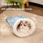 Cat resting inside a soft flannel sleeping bag nest with plush white lining on a beige rug indoors