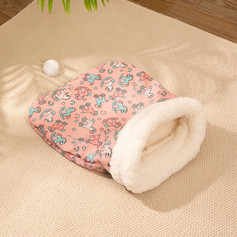 Cozy pink flannel cat sleeping bag nest with soft white fleece lining and playful animal print design on beige carpet.