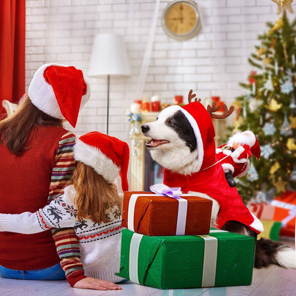 Dog wearing Santa Claus and reindeer costume next to wrapped Christmas presents with family in festive living room