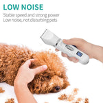 Load image into Gallery viewer, Hand holding a white electric hair clipper with LCD display grooming a calm brown curly-haired dog with fur clippings nearby.
