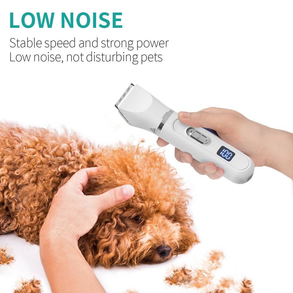Hand holding a white electric hair clipper with LCD display grooming a calm brown curly-haired dog with fur clippings nearby.
