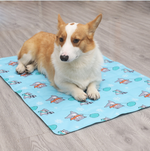 Load image into Gallery viewer, Corgi dog resting on a blue cooling dog mat with ice gel and winter-themed patterns on a wooden floor.
