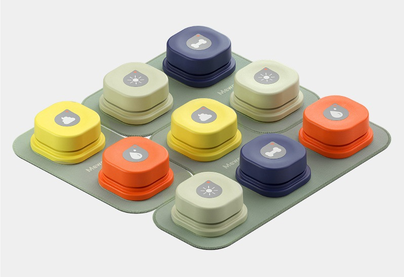 Set of colorful recordable talking buttons for dogs and cats with symbols for pet communication on a green base.