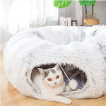 Load image into Gallery viewer, White fluffy foldable cat tunnel nest with a small playful cat inside on wooden floor near plants and books.
