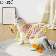 White and gray cat playing with a yellow collapsed spring cat tunnel toy with attached mouse and feather inside a home setting