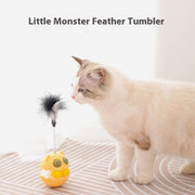 Cat playing with rotating feather tumbler toy with catnip and track ball on a striped surface