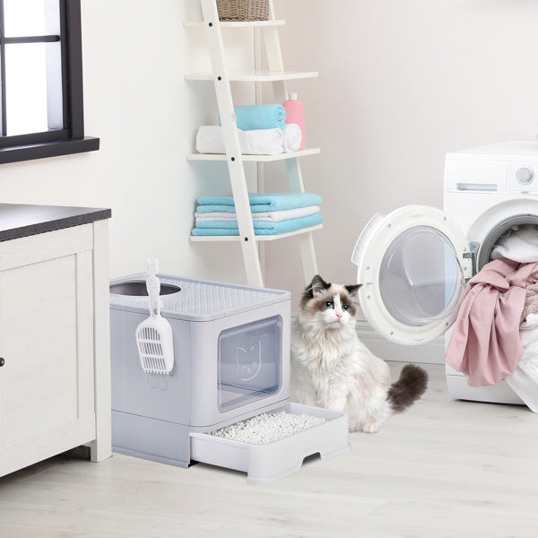 Grey enclosed cat litter box with slide-out tray and top exit placed in modern laundry room with cat nearby