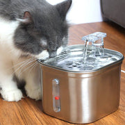 Cat drinking from a wireless induction stainless steel automatic pet water dispenser on a wooden floor.