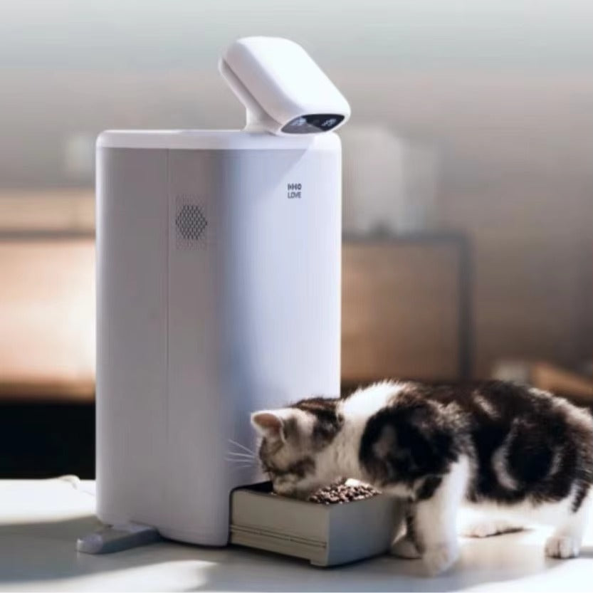 Automatic cat feeder with camera, portion control, 1080P HD video, night vision, two-way audio, and laser teaser in use by a cat.