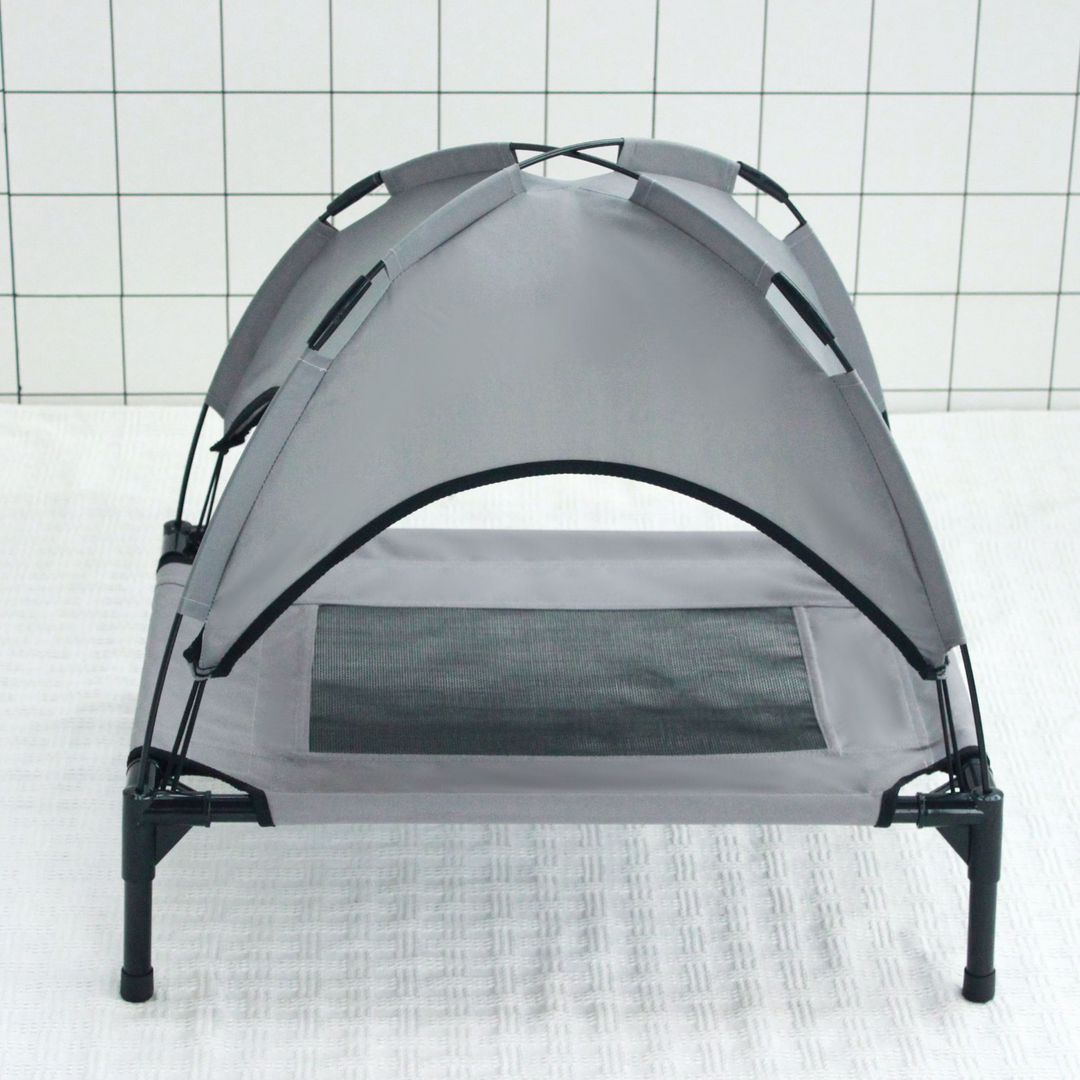 Gray elevated pet tent bed with breathable mesh and summer shade canopy on black legs against tiled background